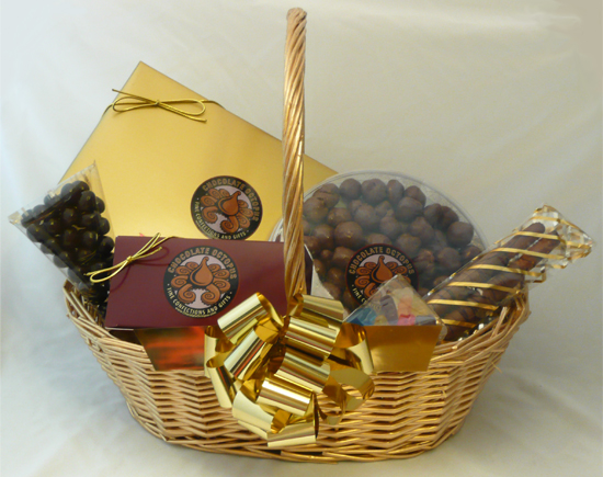 Gold Gift Basket - This traditional gold basket contains a twelve-piece assortment of our Signature Chocolates in our signature box, a large round container of chocolate covered caramel corn, a four piece box of cashew octopi, two pretzel rods dipped in caramel and chocolate and two small containers filled with gummy bears and dark chocolate covered coffee beans. Shrink wrapped with a decorative bow. 